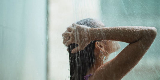 Head and shoulders of a woman taking a shower. Focusing on how natural handmade body soap is a better option than body wash.